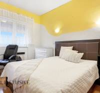 A bedroom in a family house with a bed, an armchair, and a floor with a wooden decor.
