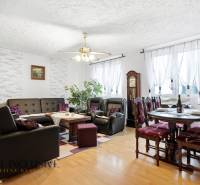 Living room in a family house with a wood-patterned floor, a sofa, and a dining table.