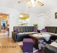 Living room in a family house with a wooden decor floor and black leather sofas.