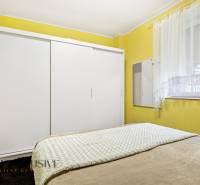 Bedroom in a family house with a simple white wardrobe and yellow walls.