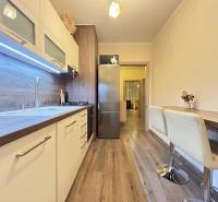 A kitchen in a 2-room apartment with a wooden decor floor and a dining area.