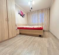 Bedroom in a 2-room apartment with wood-patterned flooring, a bed, and a wardrobe.