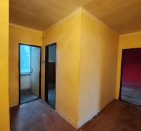 A hallway with three rooms in a 2-bedroom apartment with a wood-patterned floor.