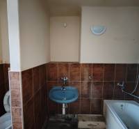 A bathroom in a 2-room apartment with a bathtub, sink, and toilet, tiled.