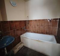 A bathroom with brown tiles, a bathtub, and a blue sink in a 2-room apartment.