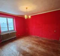 A room with red walls and a wooden decor floor in a 2-room apartment.