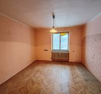 A room in a 2-room apartment with a wooden decor floor and a window with a radiator.