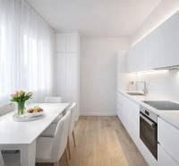 White kitchen with a dining table and a wooden decor floor in a studio apartment.