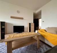 Living room of a 3-room apartment with a wooden decor floor, a sofa, and a TV stand.