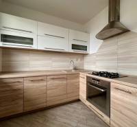 A kitchen in a 3-room apartment with a wooden decor floor and modern appliances.