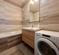 Bathroom with a bathtub, sink, and washing machine in a 3-room apartment.