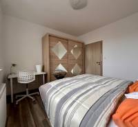 Bedroom in a 3-room apartment with a bed, wardrobe, desk, and floor with a wooden decor.