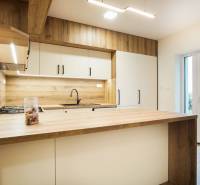 A kitchen with a wooden decor floor, bright atmosphere, and a view of the garden.
