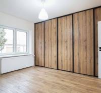 A room with a wooden decor floor and a large built-in wardrobe in a family house.
