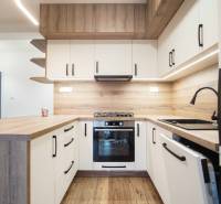 A kitchen in a family house with white cabinets and a wooden decor floor.