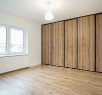 A room in a family house with a wooden decor floor and a large built-in wardrobe.