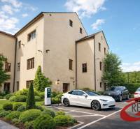 A building in Veľké Uherce with greenery and a charging station for electric cars in the parking lot.