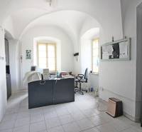 Office in a building with curved ceilings, a desk, and two windows.