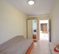 A room in a 3-room apartment with a sofa, built-in wardrobe, and a floor with a wooden decor.