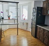 A kitchen in a family house with a wooden decor floor, dark furniture, and a bar counter.