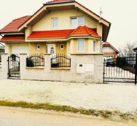 A family house in Ratkovce with a red roof, fenced entrance gate, landscaped garden.