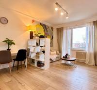 Living room in a two-room apartment with a wooden decor floor and light furniture.