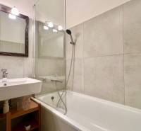 Bathroom with a bathtub and a sink in a 2-room apartment, beige tiles.