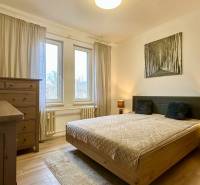 Bedroom in a 2-room apartment with a double bed, dresser, and wooden decor flooring.