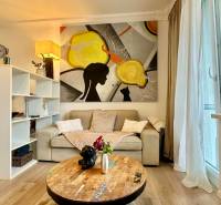 Living room in a 2-room apartment with a sofa, painting, and floor with wood decor.