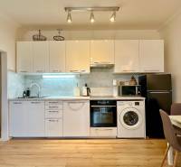 A kitchen in a 2-room apartment with white cabinets and a wood-patterned floor.