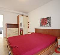 A bedroom with a wood-decor floor, a bed, a cabinet, and a painting in a 3-room apartment.