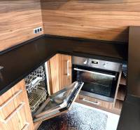 A kitchen in a studio apartment with a built-in dishwasher and wooden decor.