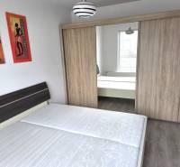 Bedroom with a double bed and a wardrobe in a studio apartment, decorative paintings on the wall.