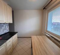 A kitchen in a 2-room apartment with ceramic tiles and a dining table.