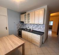 Kitchen in a 2-room apartment with tiled flooring and a wooden decor table.