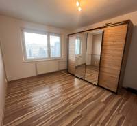 A room in a 2-room apartment with a wooden decor floor and a built-in wardrobe.