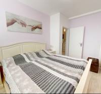 Bedroom in a family house with decorative textiles and a wooden-patterned floor.