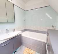 A bathroom with a bathtub in a family house, elegant accessories, and light color tones.