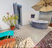 In the exterior of a family house in Stupava, there are sun loungers, a hot tub, and a sunshade.