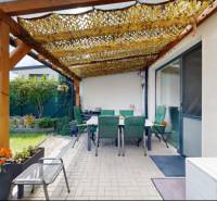 Terrace of a family house in Stupava with a pergola, chairs, and greenery in the garden.