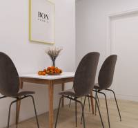 Dining area with a wooden table, four chairs, and decorative oranges in a 3-room apartment.