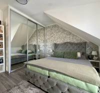 Interior of a 2-room apartment with a wooden decor floor, slanted ceiling, and mirrored wardrobe.