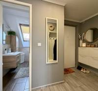 A hallway with a wooden decor floor, a mirror, and a bathroom in a 2-room apartment.