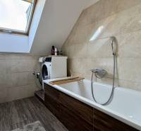 A bathroom with a skylight, a washing machine, and a wooden decor floor in a 2-room apartment.