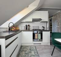 A kitchen in a 2-room apartment with a slanted ceiling and a floor with a wooden decor.