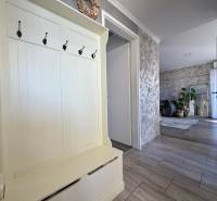 Entrance hallway in a 2-room apartment with coat hooks, leading to a living room with plants.