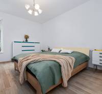 Bedroom with a bed, dresser, plants, and wood-decor flooring in a 3-room apartment.