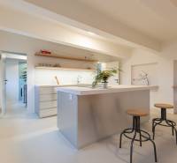 Bright kitchen with an island and high chairs in a three-room apartment, floor with wood decor.