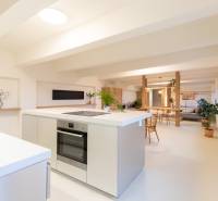 A bright kitchen with an island in a 3-room apartment, white surfaces, wooden furniture decor.