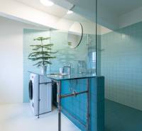 A bathroom with blue tiles, a shower, a washing machine, and a sink in a 3-room apartment.